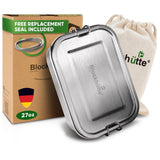 Stainless steel lunch box, 27 oz, closed, in front of a cardboard box reading Free replacement seal included