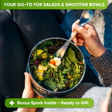 Person sitting outdoors eating mixed green salad with a spork from an open stainless steel salad bowl
