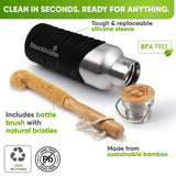 Bottle in a black silicone sleeve lying on its side next to a bamboo bottle brush with natural bristles and the bamboo cap