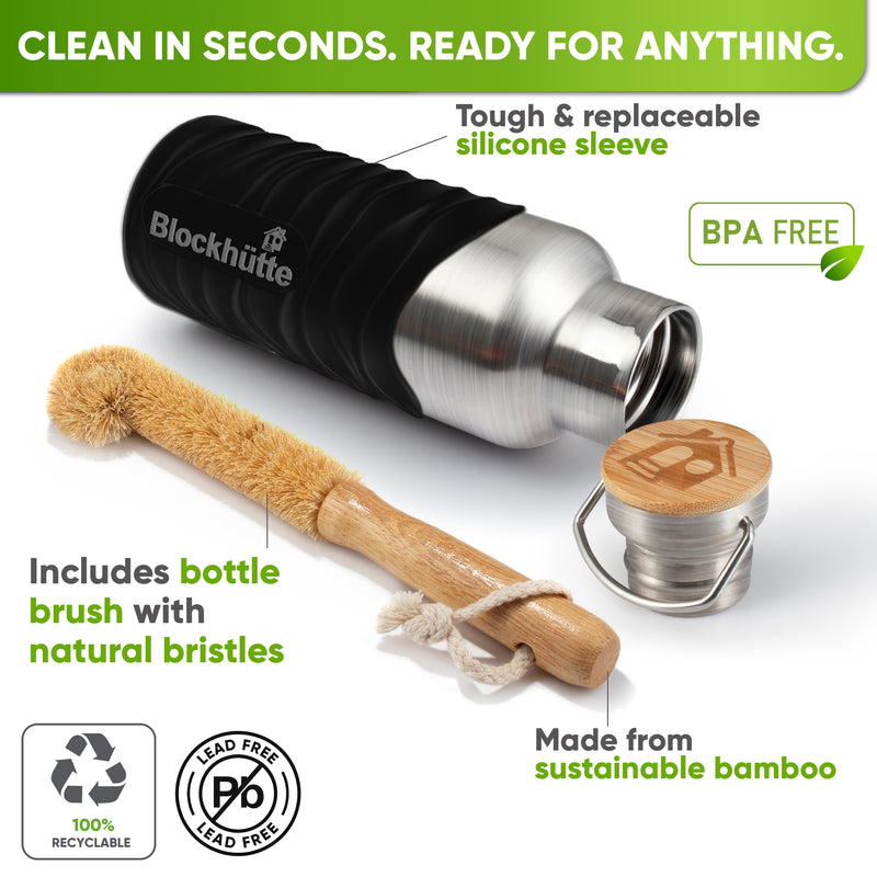Bottle in a black silicone sleeve lying on its side next to a bamboo bottle brush with natural bristles and the bamboo cap