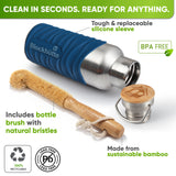 Bottle in a blue silicone sleeve lying on its side next to a bamboo bottle brush with natural bristles and the bamboo cap