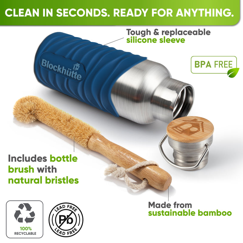 Bottle in a blue silicone sleeve lying on its side next to a bamboo bottle brush with natural bristles and the bamboo cap