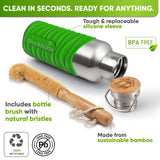 Bottle in a bright green silicone sleeve lying on its side next to a bamboo bottle brush with natural bristles and the bamboo cap