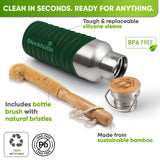 Bottle in a dark green silicone sleeve lying on its side next to a bamboo bottle brush with natural bristles and the bamboo cap